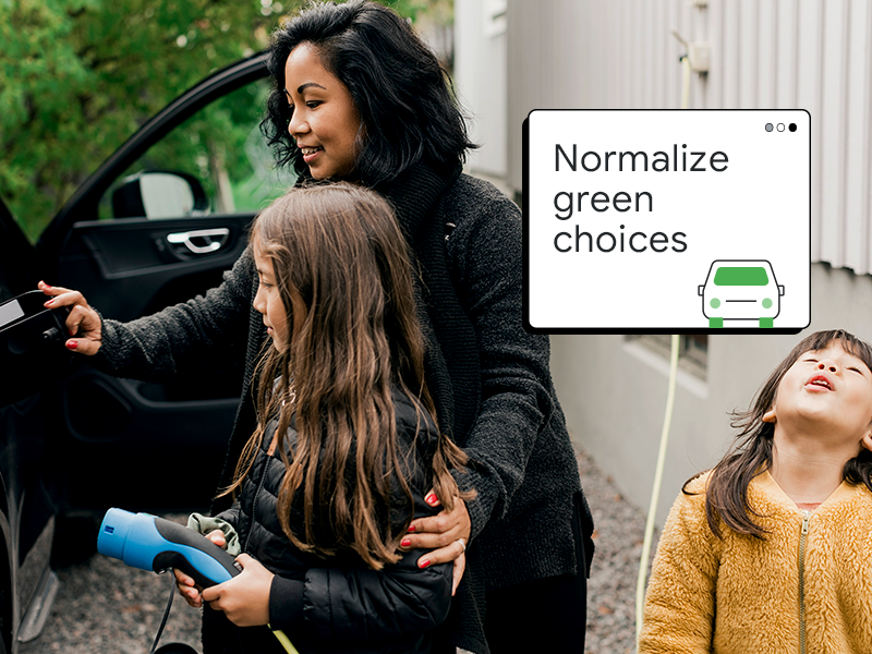 Siyah saçlı buğday tenli bir anne kızlarına elektrikli arabalarını nasıl şarj edeceklerini gösteriyor. Bir pop-up pencerede "Doğayı koruyan tercihleri normalleştirin." yazıyor.