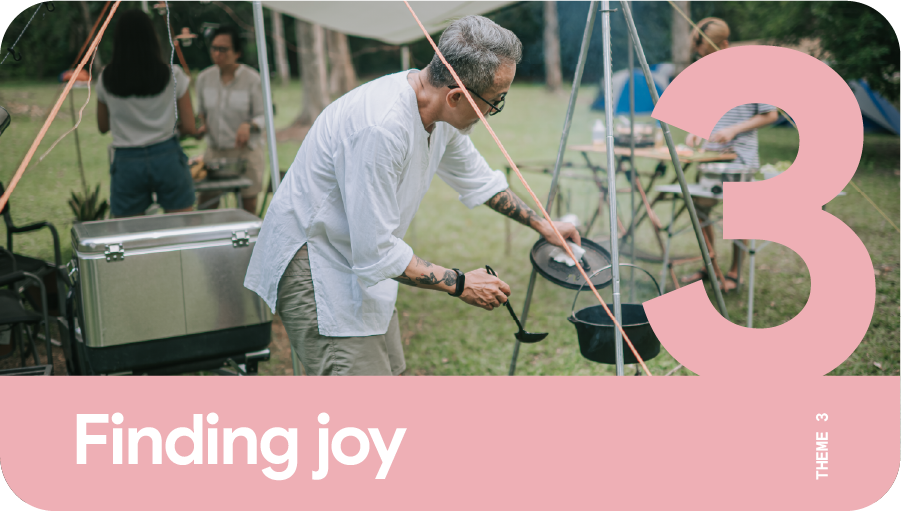 Theme 3: Finding joy. A man with gray hair cooking outdoors during an overseas camping trip.