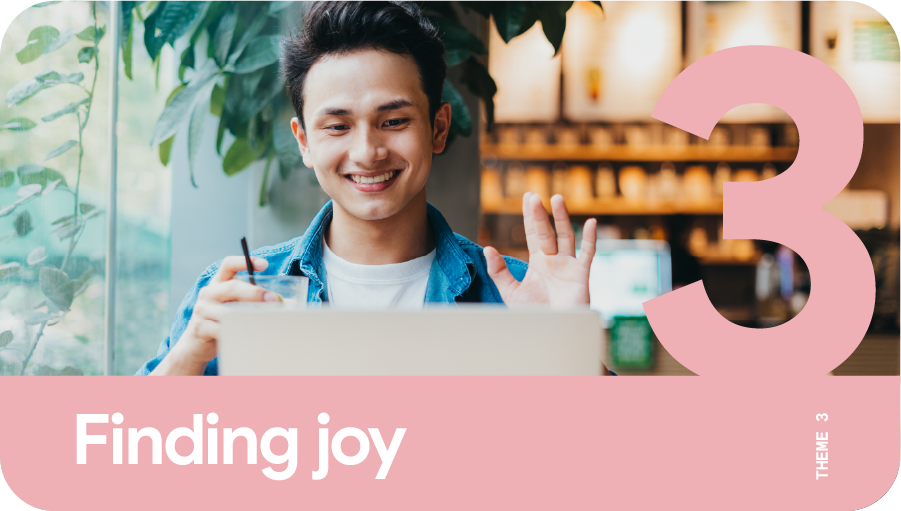 Theme 3: Finding joy. A young man waving at his laptop during a video call as he works remotely.