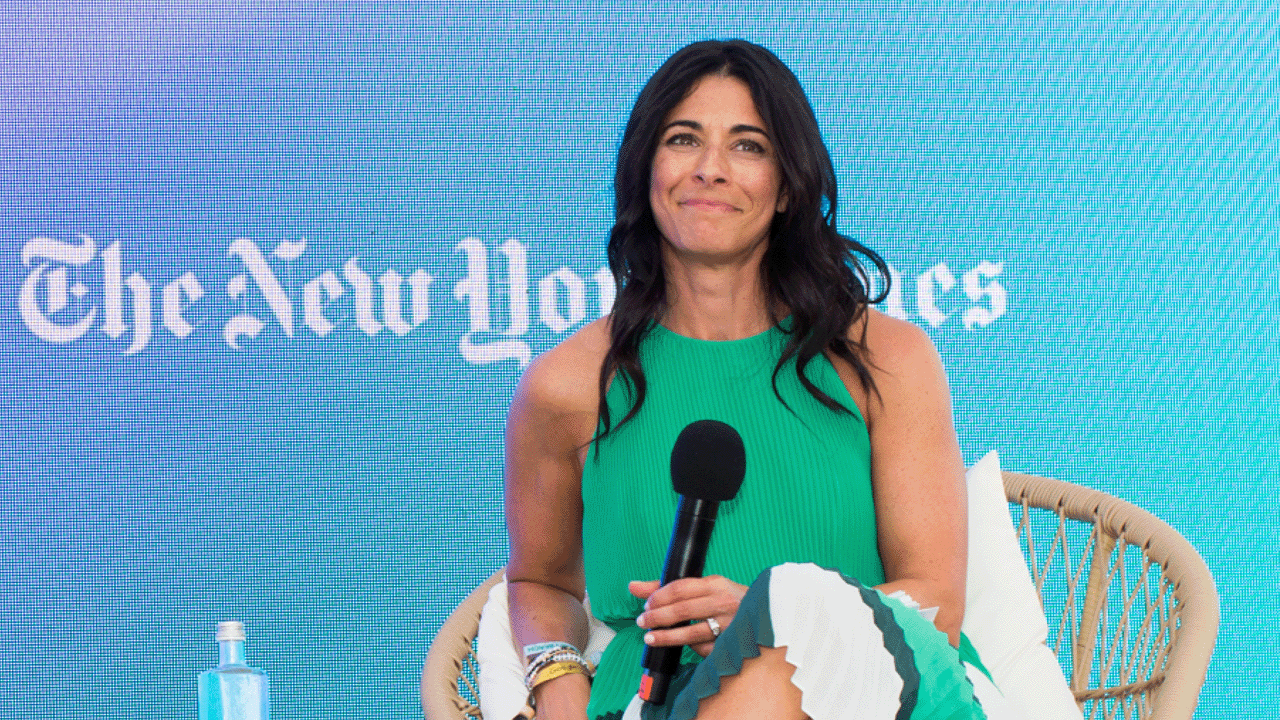 Joy Robins, global chief advertising officer, The New York Times, speaks at the 2023 Cannes Lions Festival of Creativity. Robins, wearing a green dress, sits in a rattan chair in front of an LED screen with “The New York Times” logo.