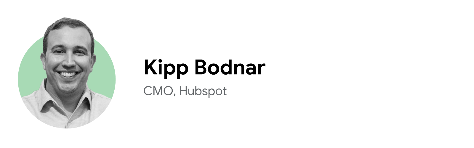 Kipp Bodnar, CMO of Hubspot, smiles gregariously in a close-cropped black-and-white headshot with a pale green background. Bodnar has short dark hair, dark eyes, and light skin, and wears a white, button-down shirt.